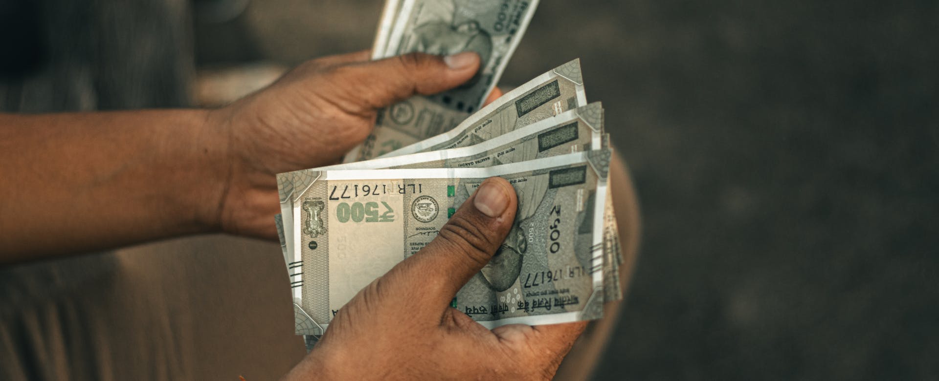 Man counting Indian rupee notes for third banner